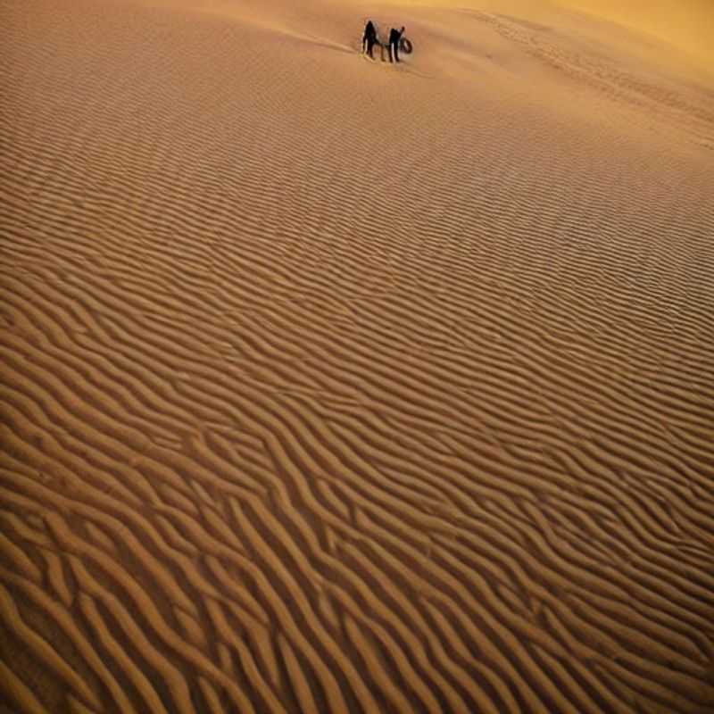 Golden sand dunes stretch towards the horizon in the vast Sahara Desert of Morocco/Tunisia, a landscape of scorching beauty – but is it *really* ideal for your summer holiday? (Hint: Bring lots and lots of water!).