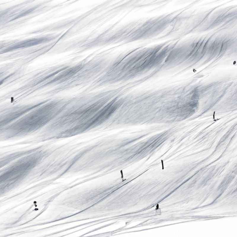 A lone skier glides effortlessly down the pristine slopes of Les Arcs, France, surrounded by breathtaking alpine vistas, on a 5-day solo skiing adventure during the height of the season.