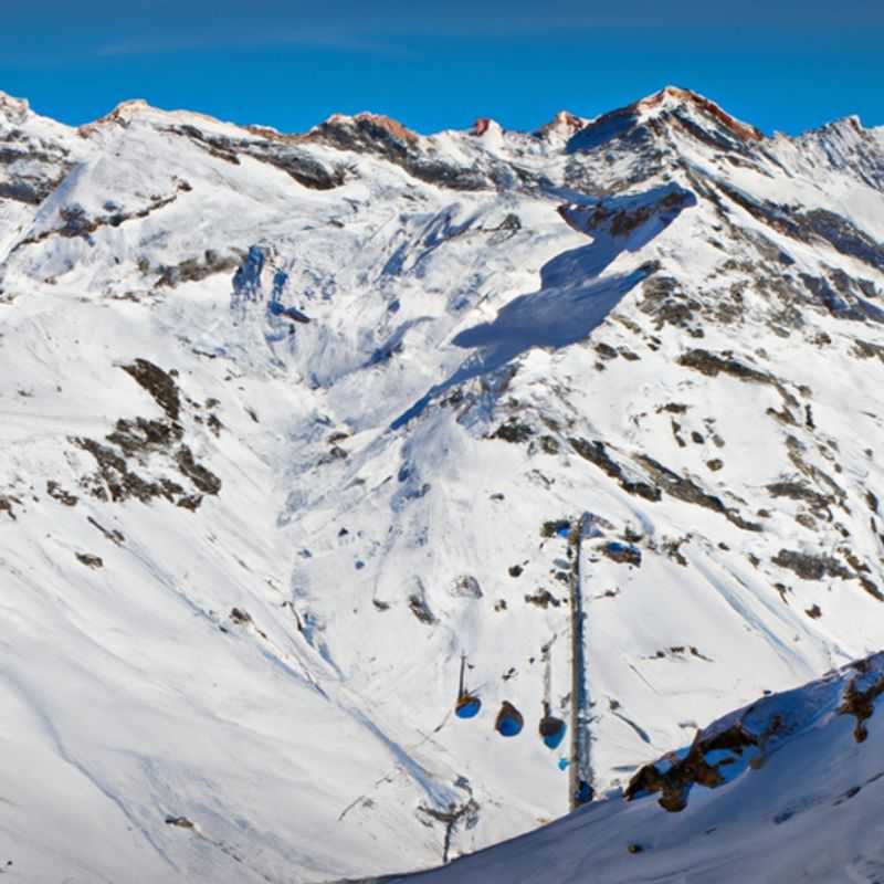A solitary figure glides down a pristine slope against the breathtaking backdrop of snow-capped peaks and azure skies in Andermatt, Switzerland, embarking on a thrilling 3-day solo skiing adventure.